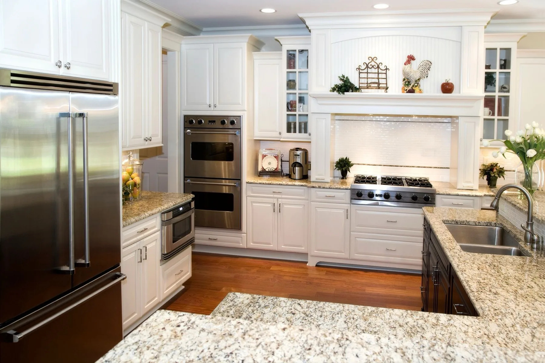A finished kitchen with white cabinetry and granite countertops